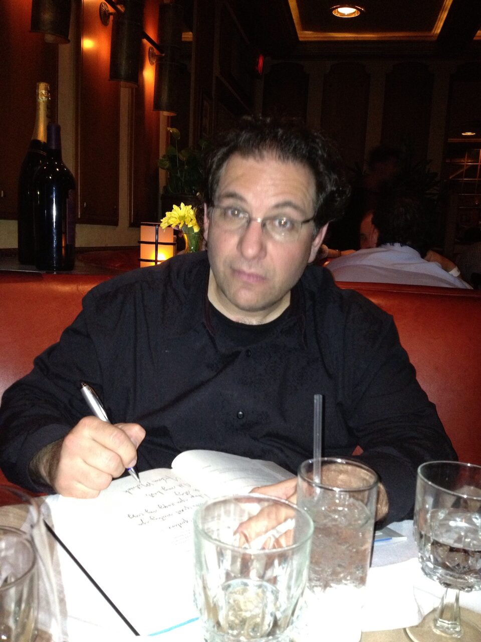 Kevin Mitnick autographing a copy of his book at a restaurant table