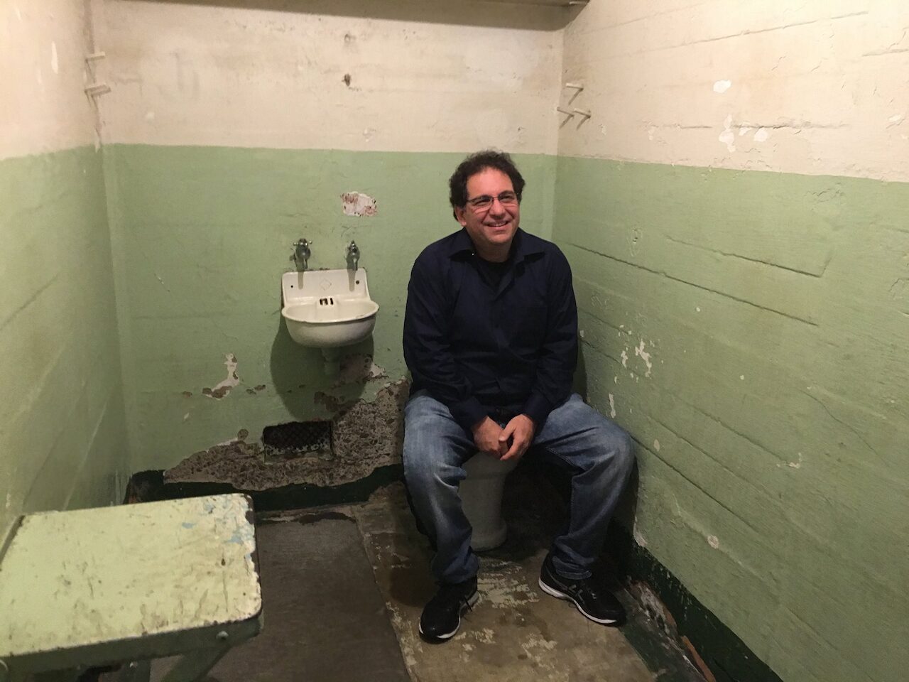 Kevin Mitnick sitting in an empty Alcatraz prison cell