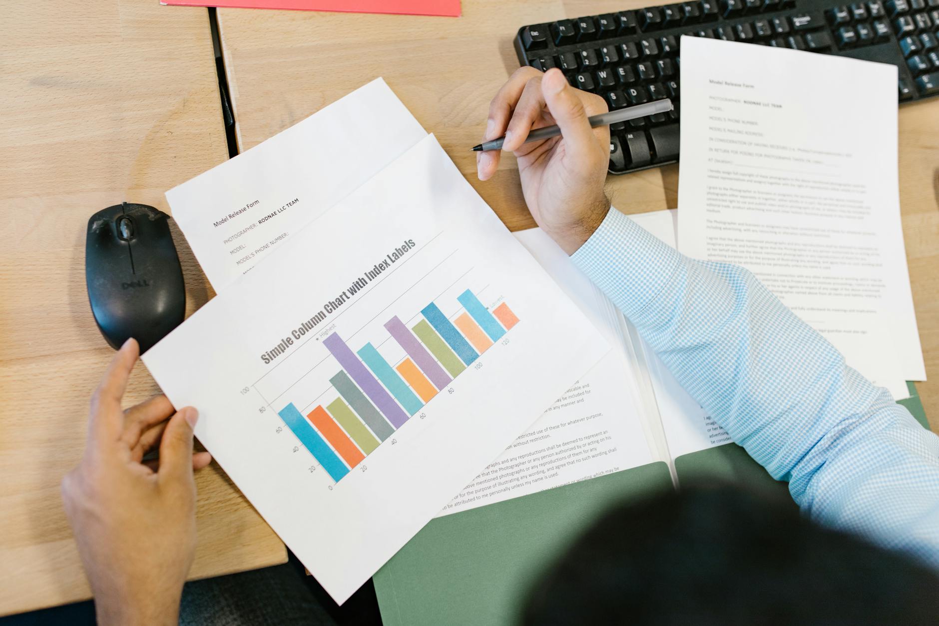 A business analyst reviews a colorful bar chart and documents at a desk