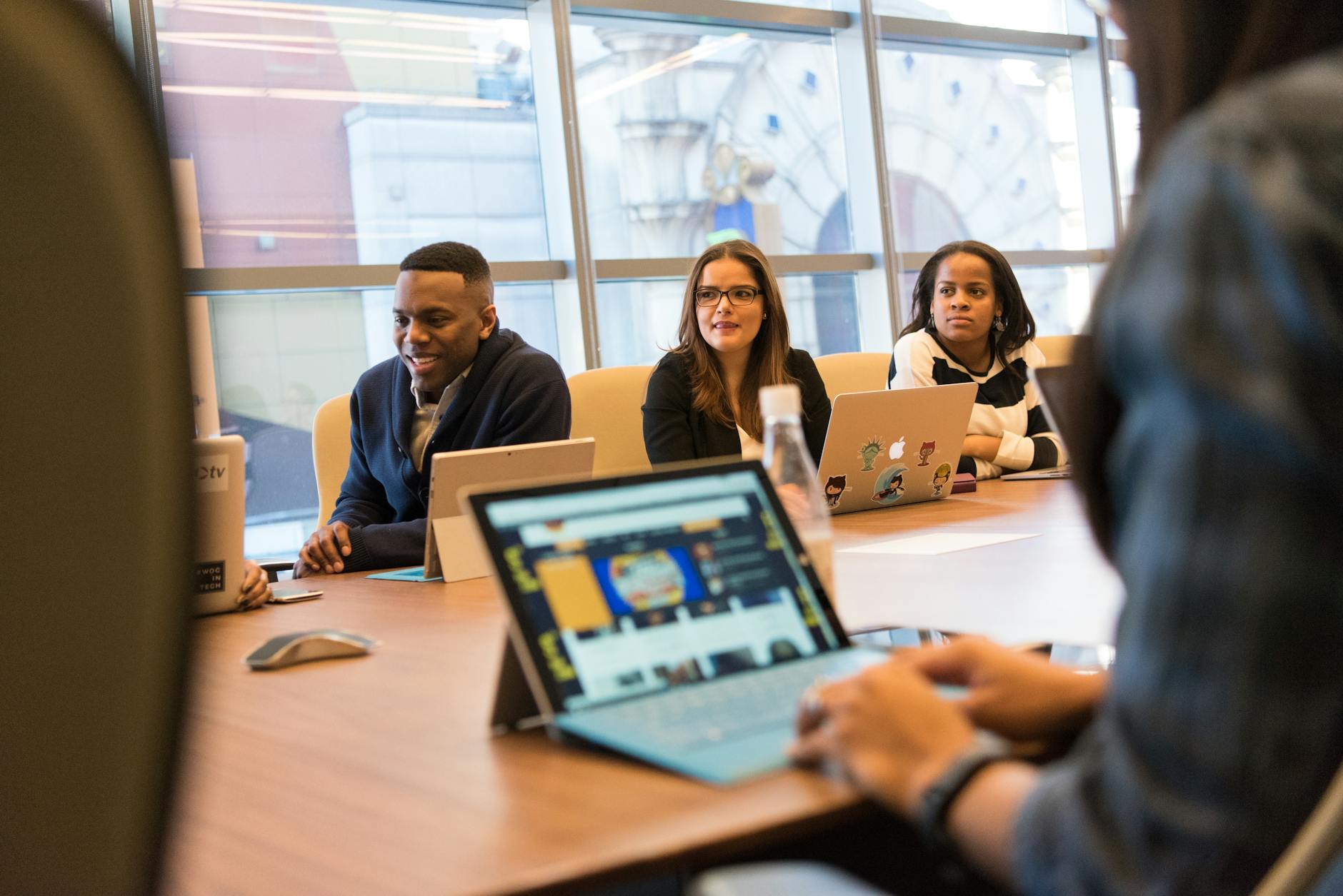 A diverse group of professionals collaborating on laptops in a modern office