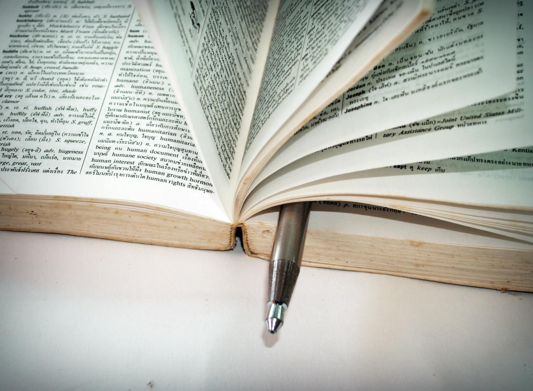Close-up of an open dictionary with a pen separating the pages
