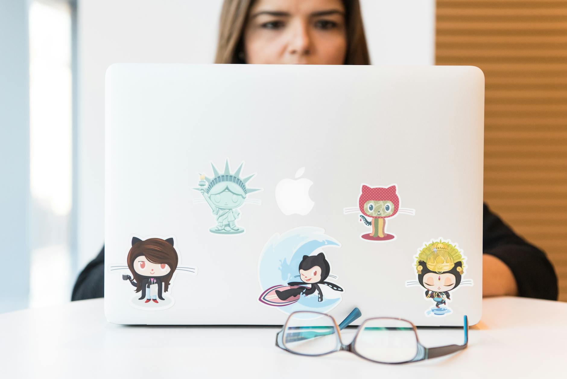 Woman focused on laptop with colorful GitHub-themed stickers