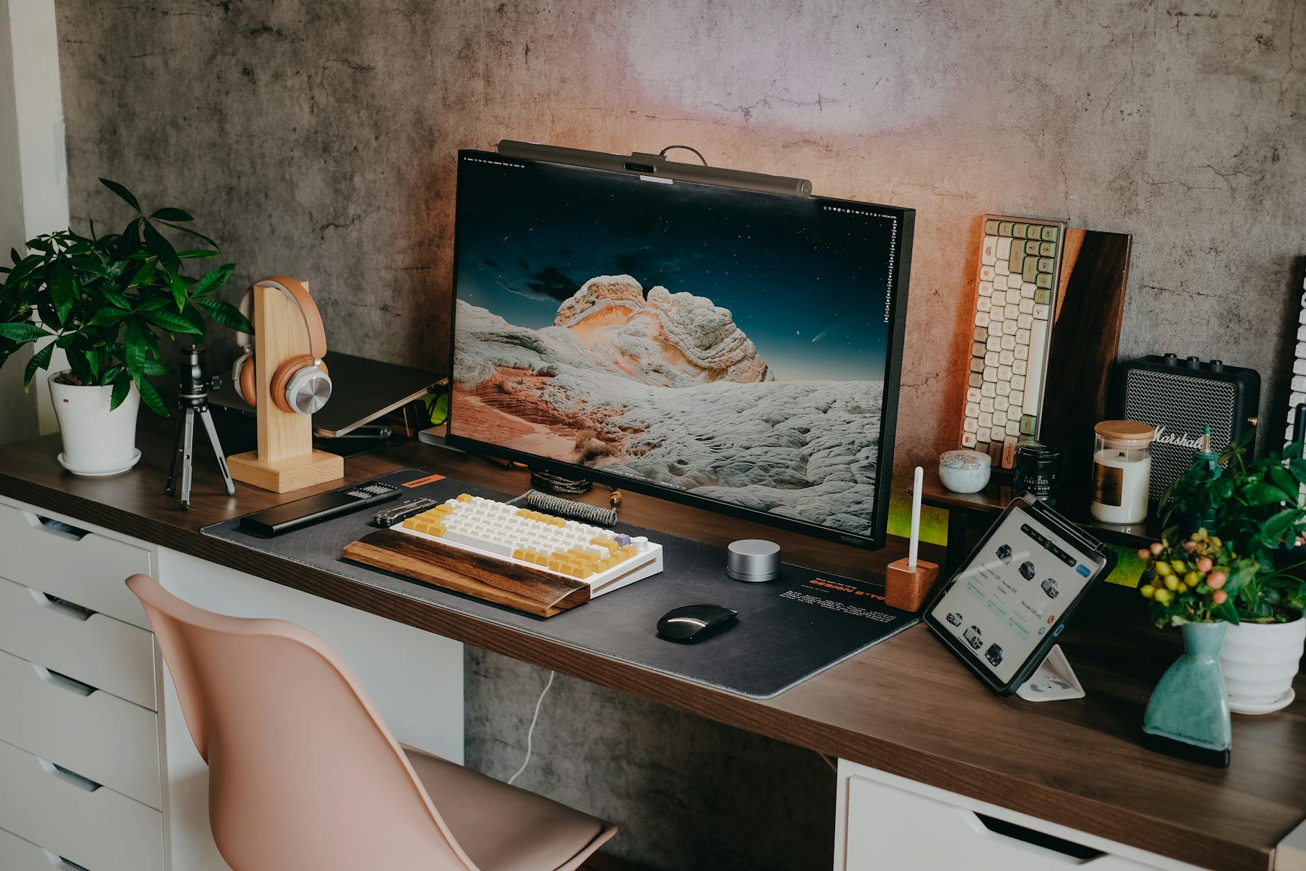 Stylish home office desk setup featuring a mechanical keyboard, monitor, plants, and tech gadgets