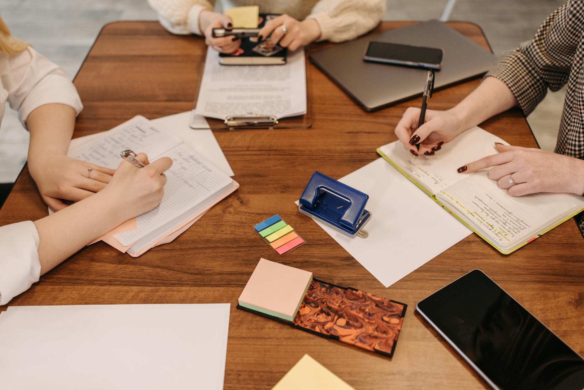 Three colleagues engaged in a collaborative meeting taking notes and reviewing documents
