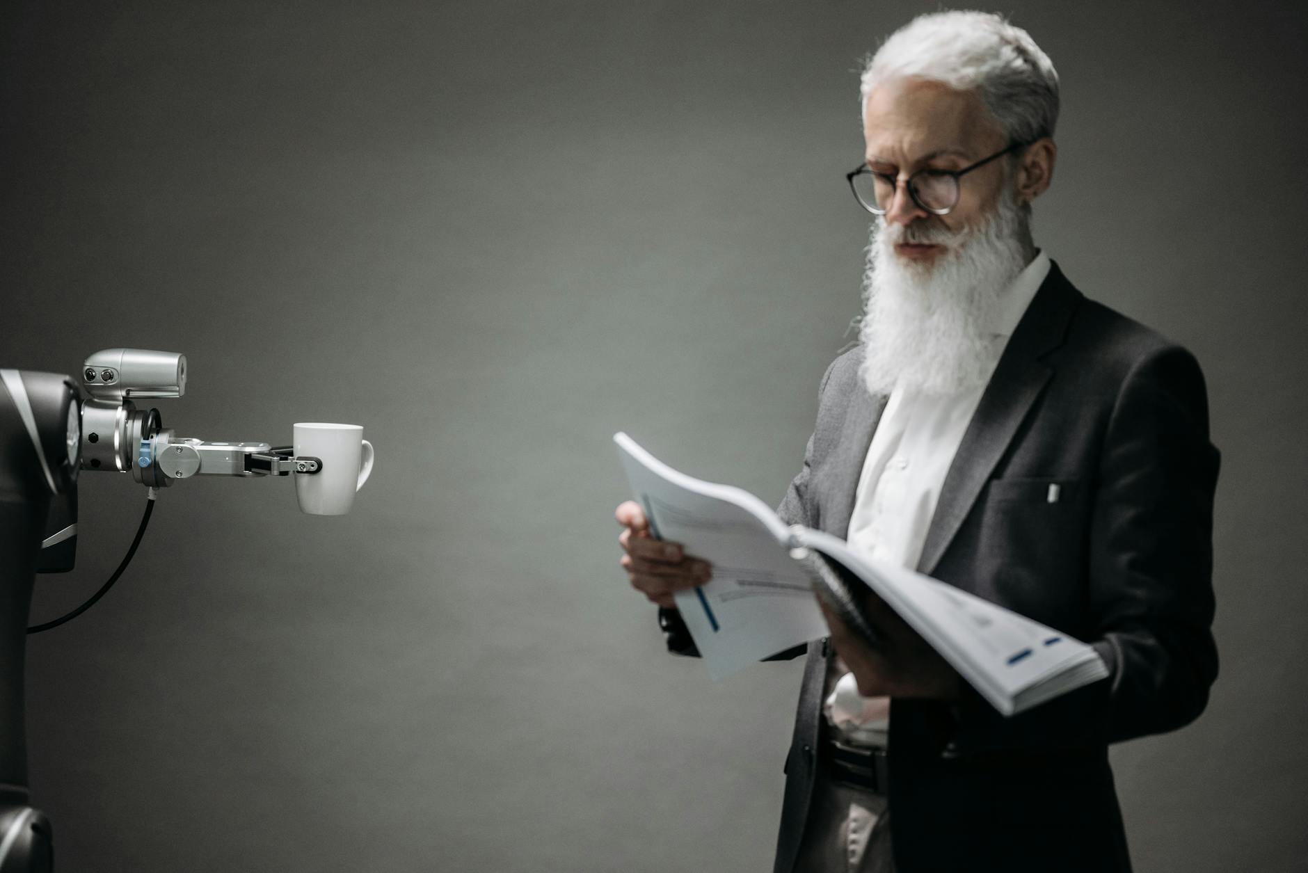 A robot arm assists a professional with a book and coffee in a modern office
