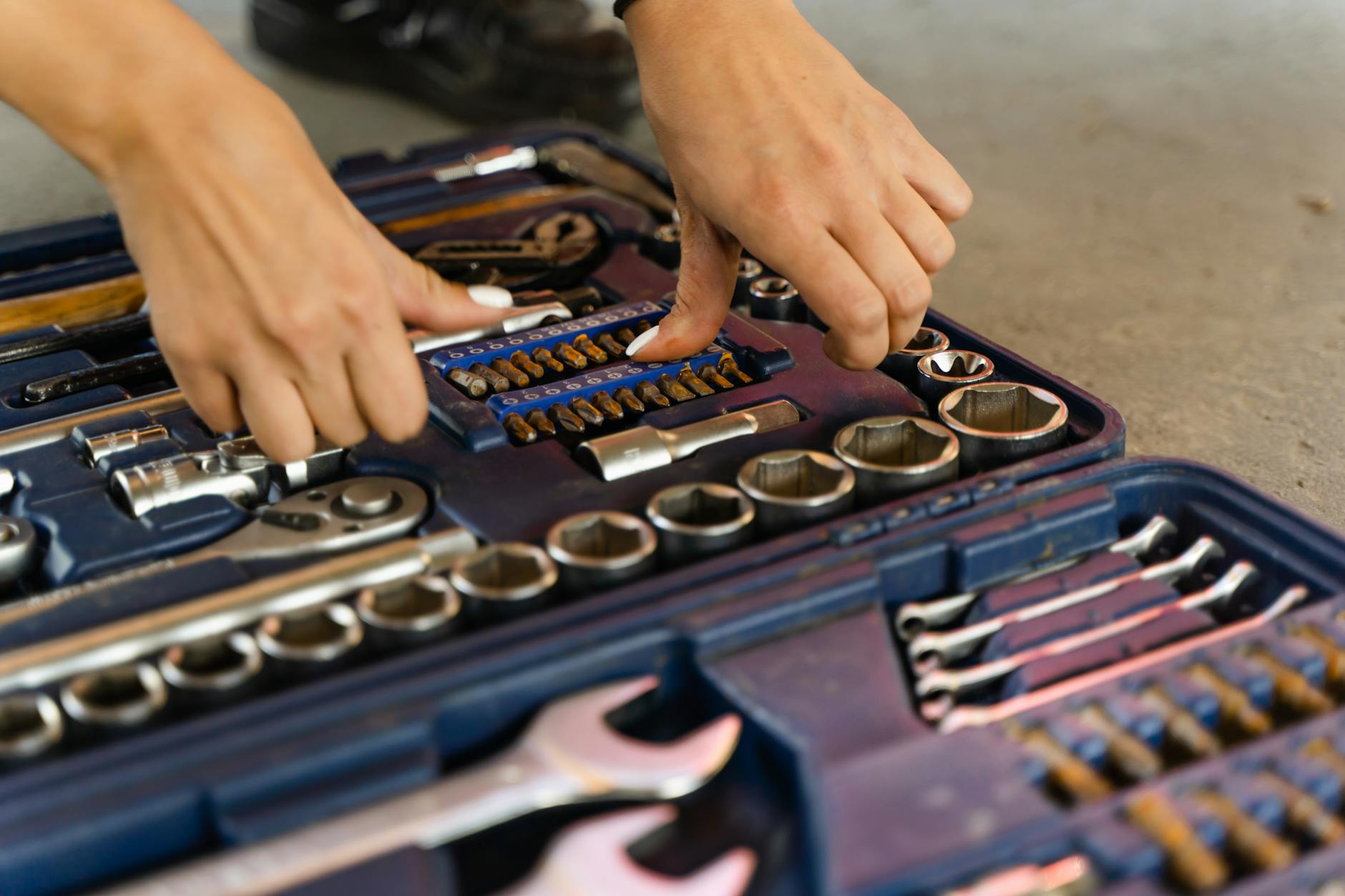 Hands selecting tools from a well-organized toolbox